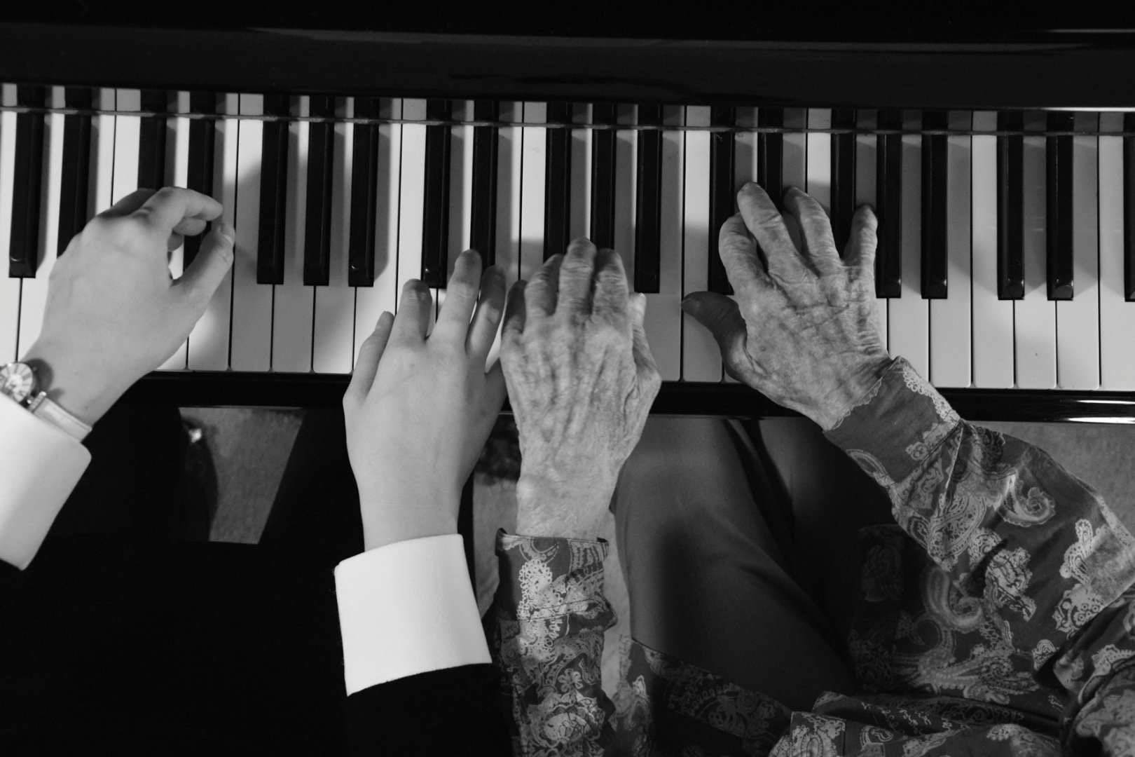 Four hands playing together at the piano